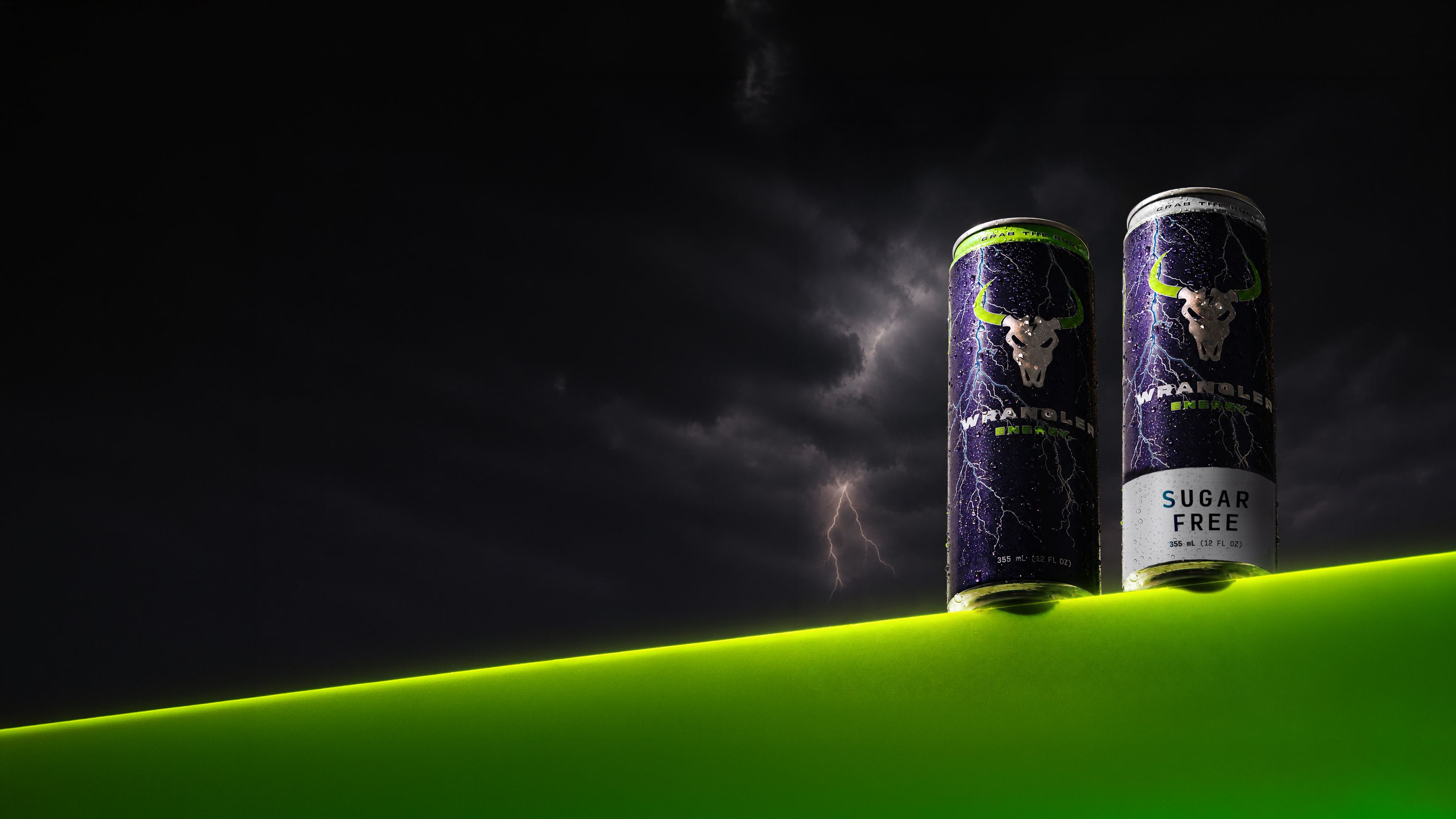 Wrangler Energy Original and Sugar Free cans on a glowing green ledge under a lightning storm